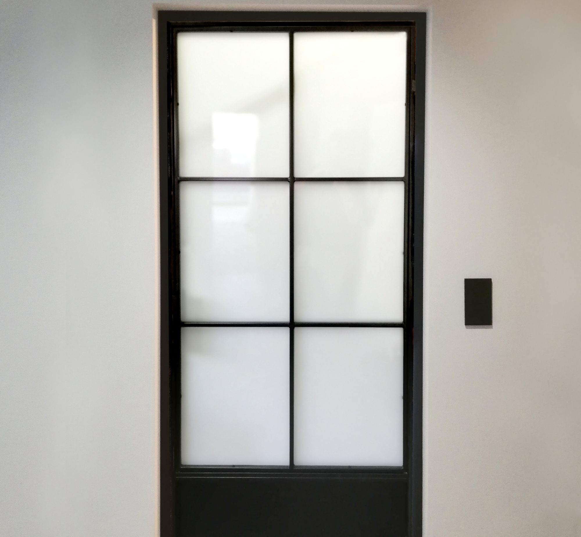 Metal and glass industrial door with lower steel infill and milk glass